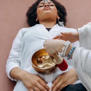 A woman experiences crystal healing therapy with a singing bowl in a serene setting.